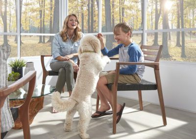 image shows family in EZE Breeze sunroom from DIY Patio Windows